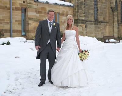 A bride and groom in the snow at St Mary's